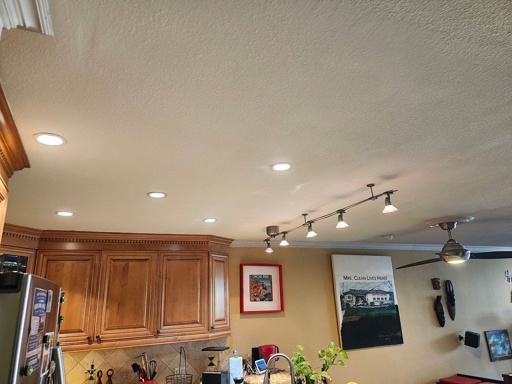 Kitchen interior with wooden cabinets, recessed lights, and framed wall art on beige walls