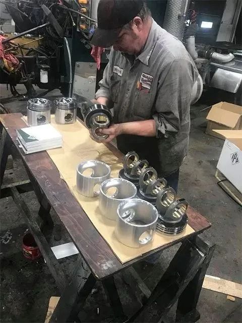 Mechanic inspecting engine pistons on a workbench in a workshop.