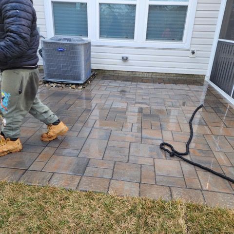 A person is walking on a brick sidewalk in front of a house.
