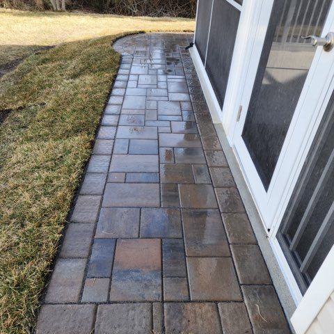 A brick walkway leading to a screened in porch