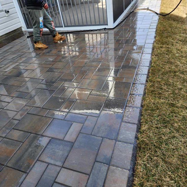 A man is standing on a brick walkway next to a screened in porch