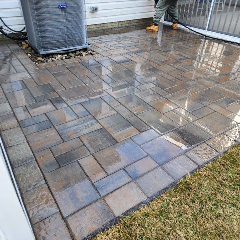 A man is cleaning a patio with a pressure washer.