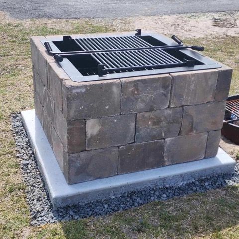 A grill made out of bricks is sitting in the grass