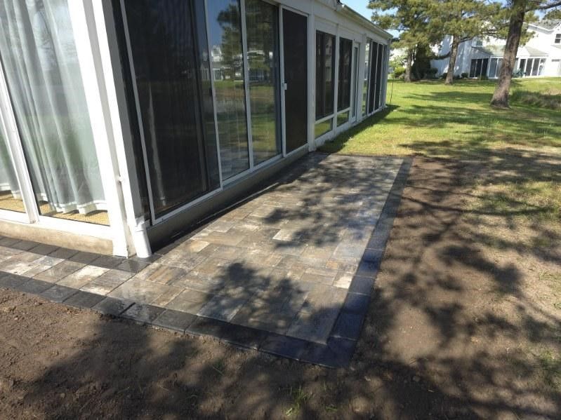 There is a patio in front of a house with sliding glass doors.