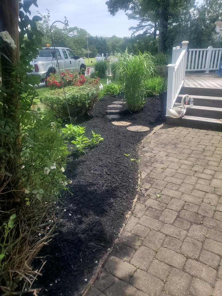 A brick walkway leading to a deck with a white railing.