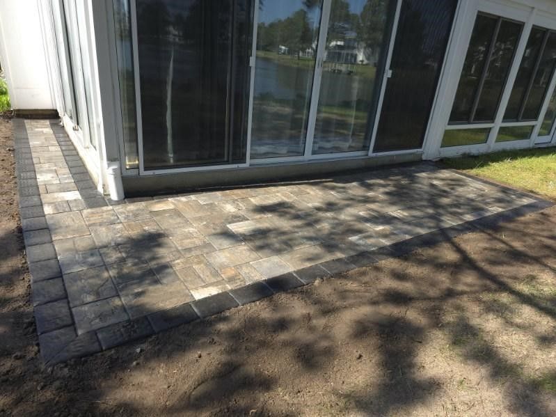A patio with a sliding glass door in the backyard of a house.