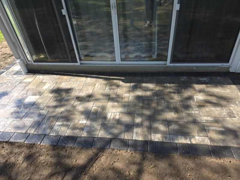 A patio with a sliding glass door and a shadow of a tree on it.
