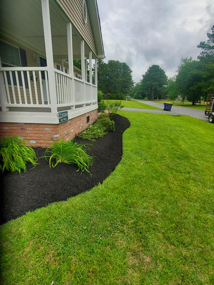 A house with a porch and a lush green lawn.