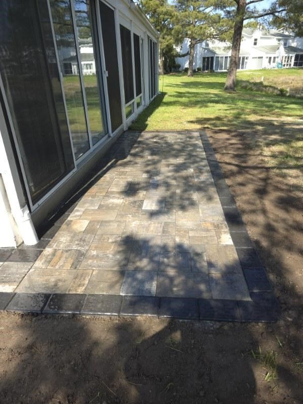 A patio is being built in front of a screened in porch.