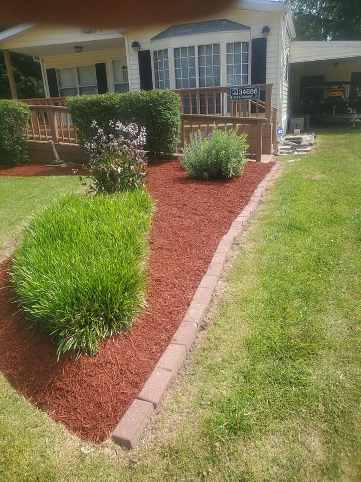 A house with a red mulch bed in front of it.