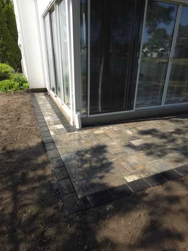 A patio is being built in front of a house with sliding glass doors.
