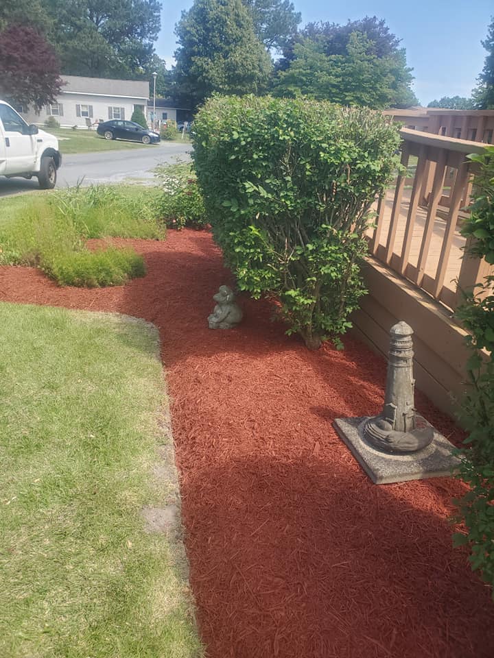 A lawn with red mulch and a statue in the middle of it.