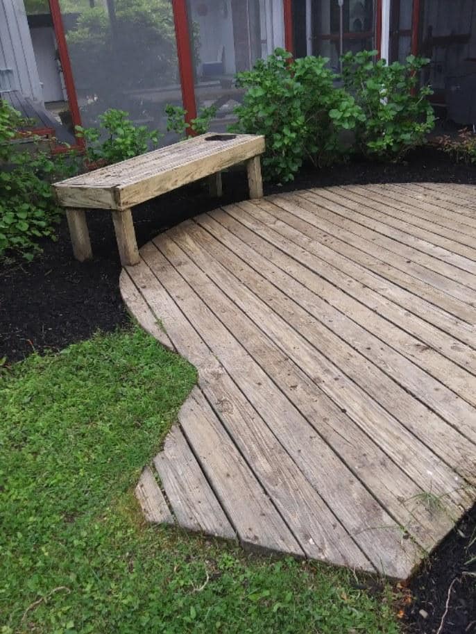 A wooden deck with a bench in the middle of it.