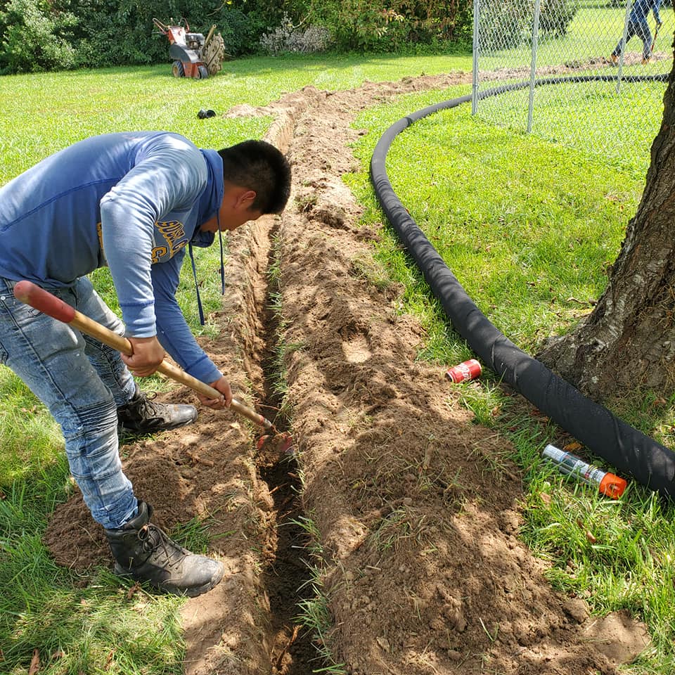 A man is digging a hole in the ground with a shovel.