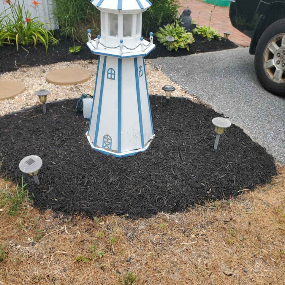 A white and blue lighthouse is in the middle of a garden