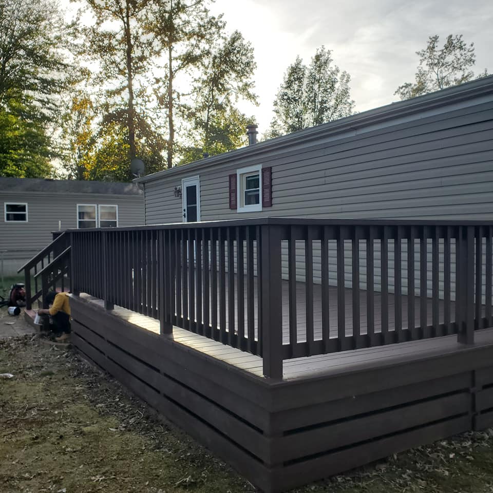 A mobile home with a large deck in front of it
