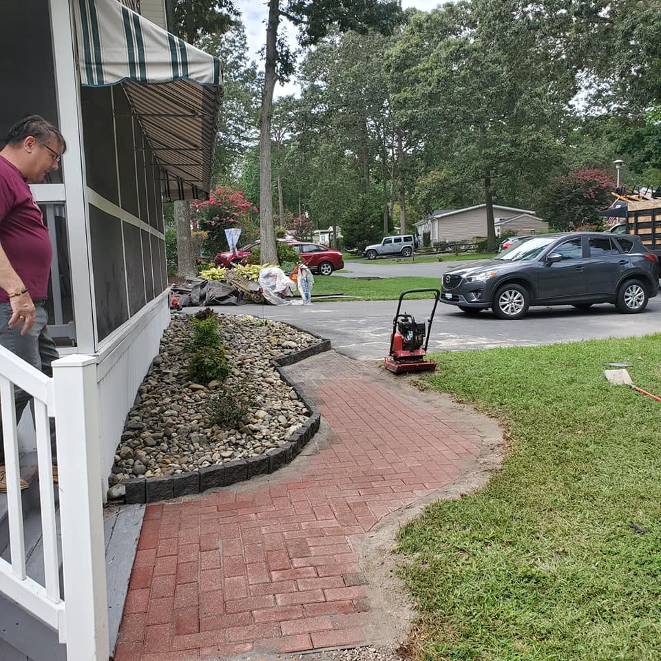 A man standing on a porch next to a brick walkway