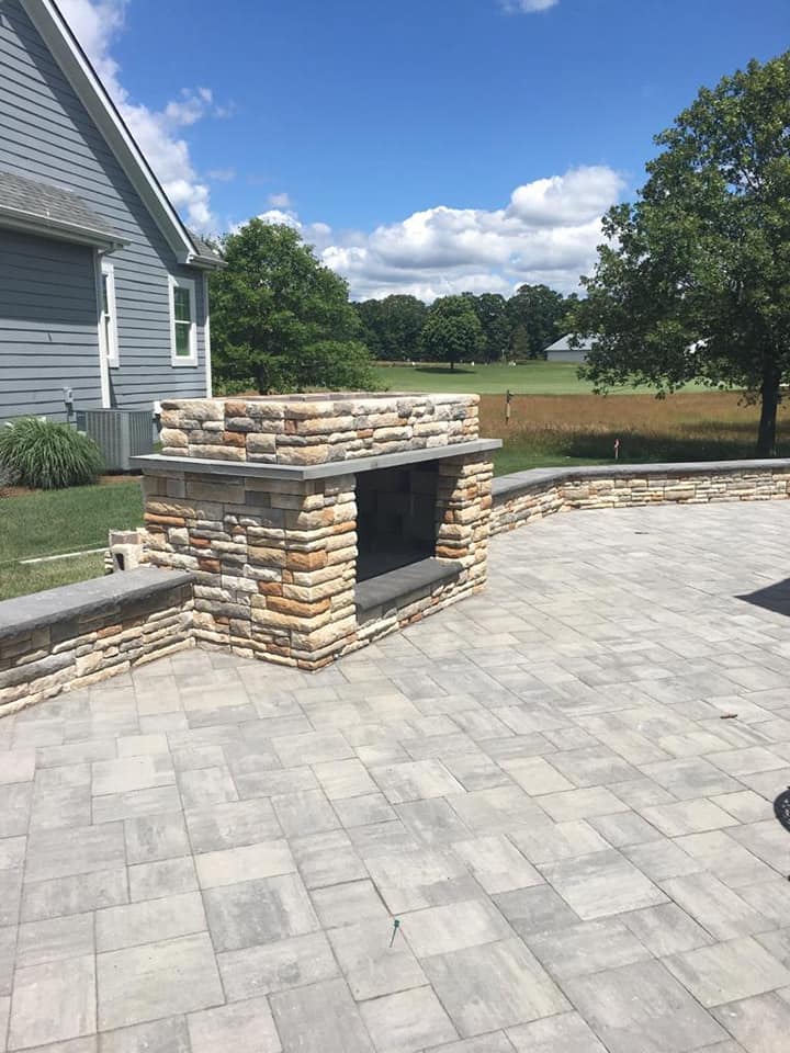 A stone fireplace is sitting on a patio next to a house.