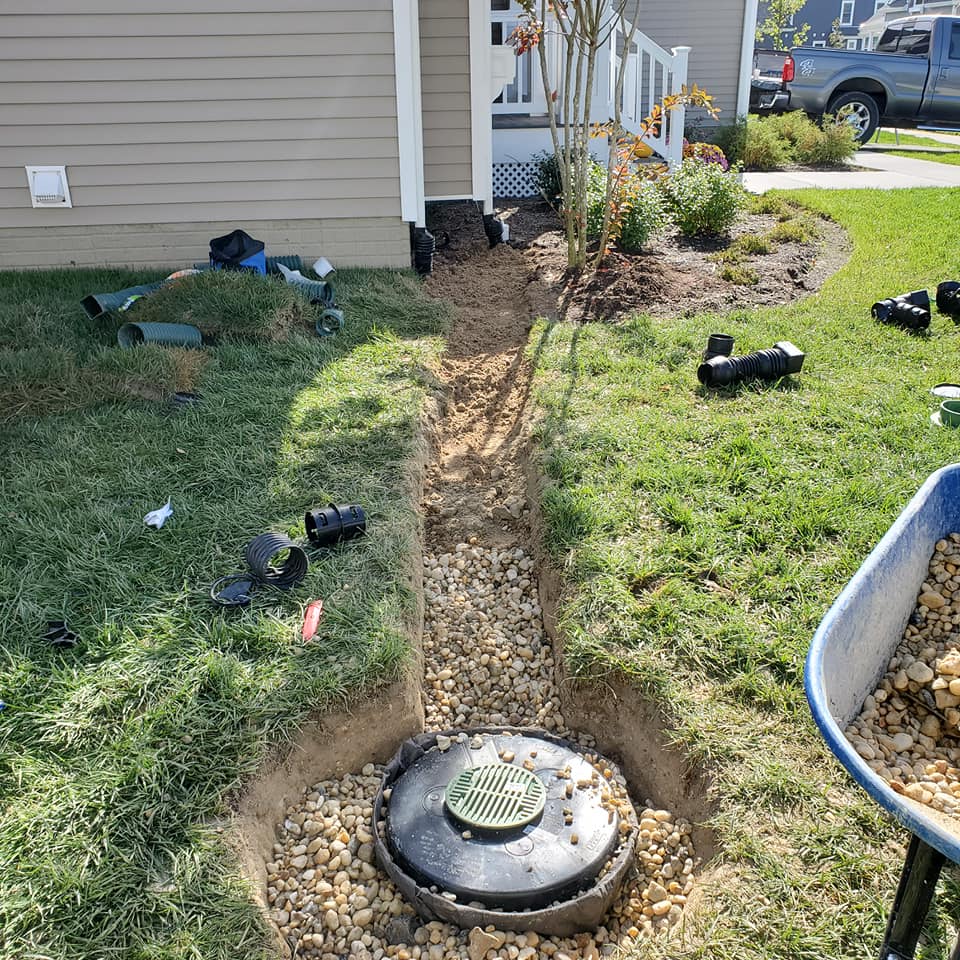 A wheelbarrow is filled with gravel in front of a house.