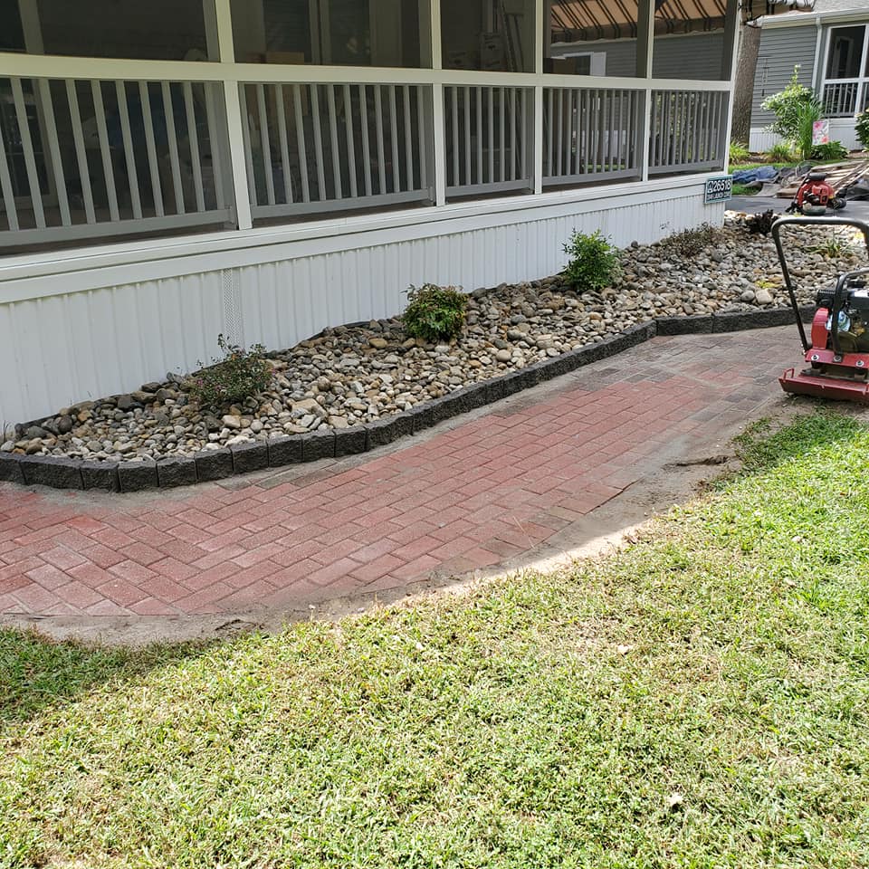 A brick walkway is being built in front of a screened in porch.