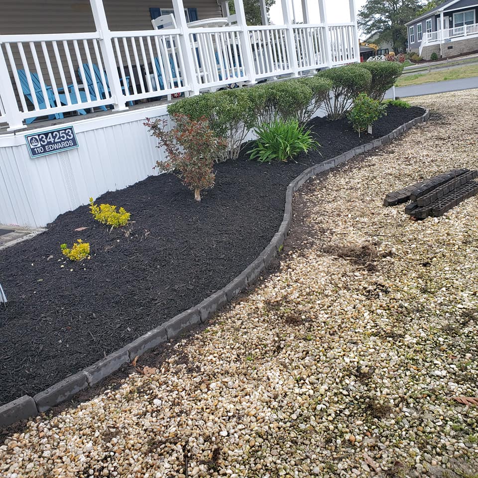 A house with a porch and a garden in front of it.