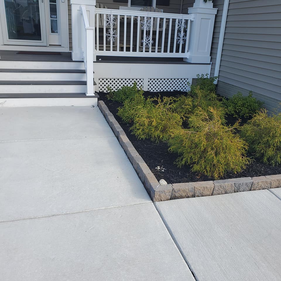A concrete walkway leading to a porch with a white railing