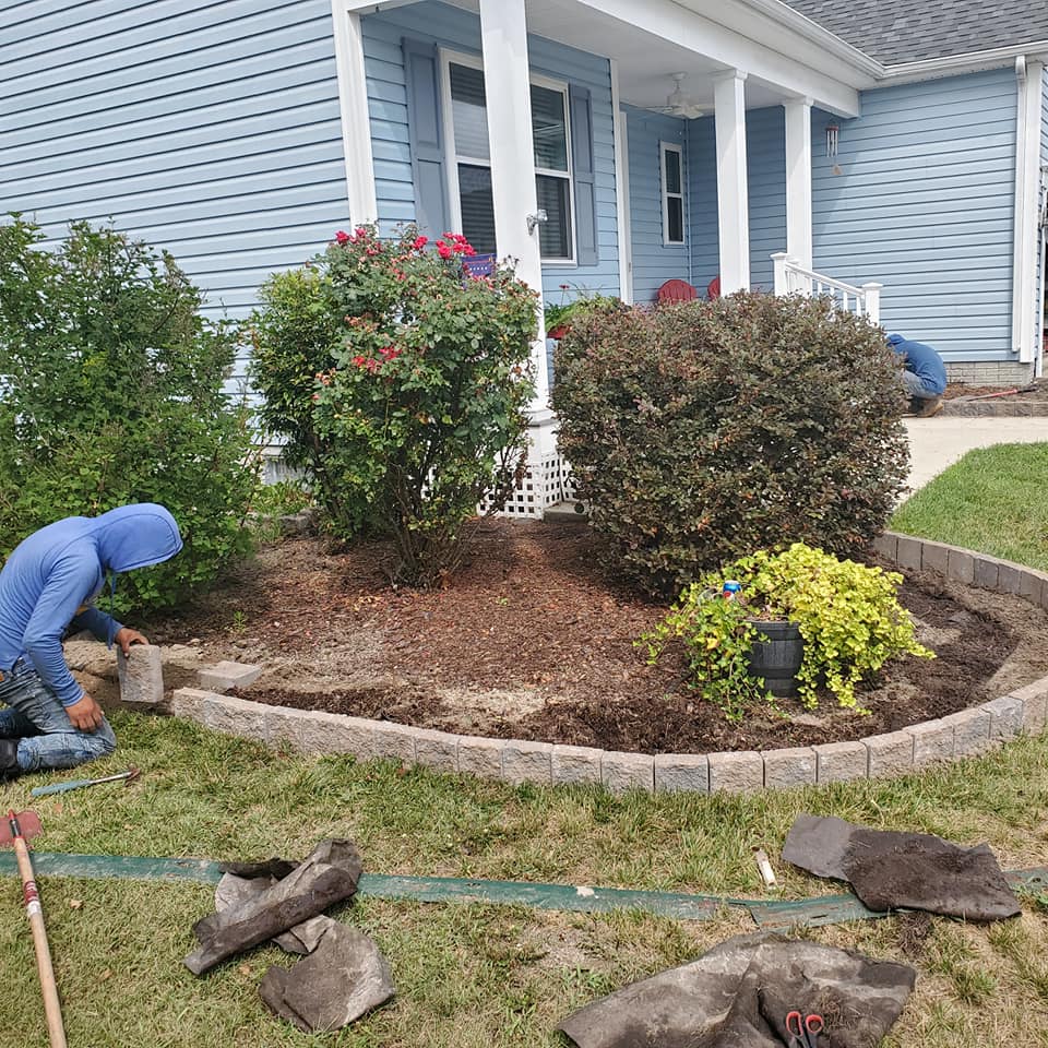 A man is working on a garden in front of a house.