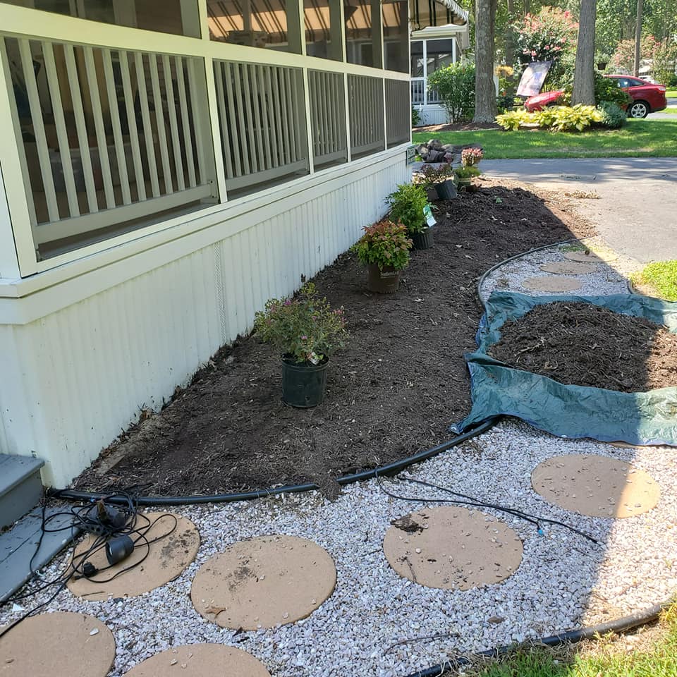 A house with a screened in porch and a garden in front of it