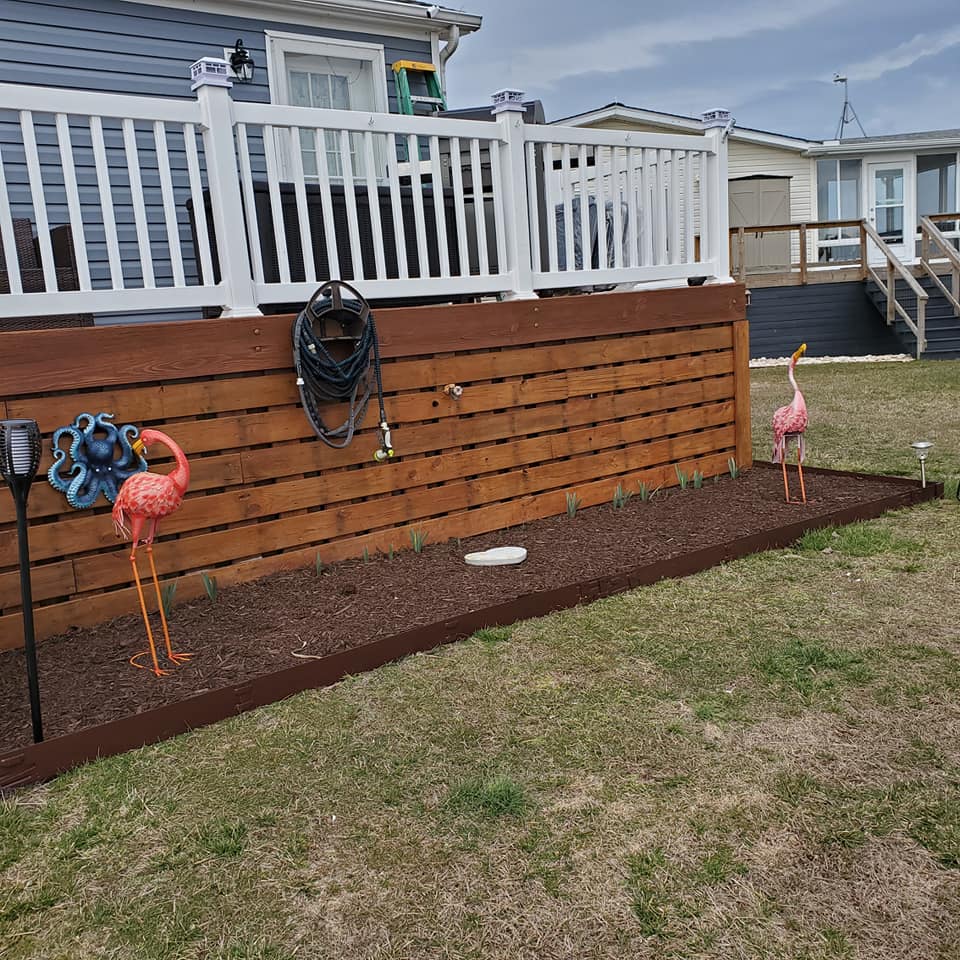 A wooden fence with flamingos and a hose on it