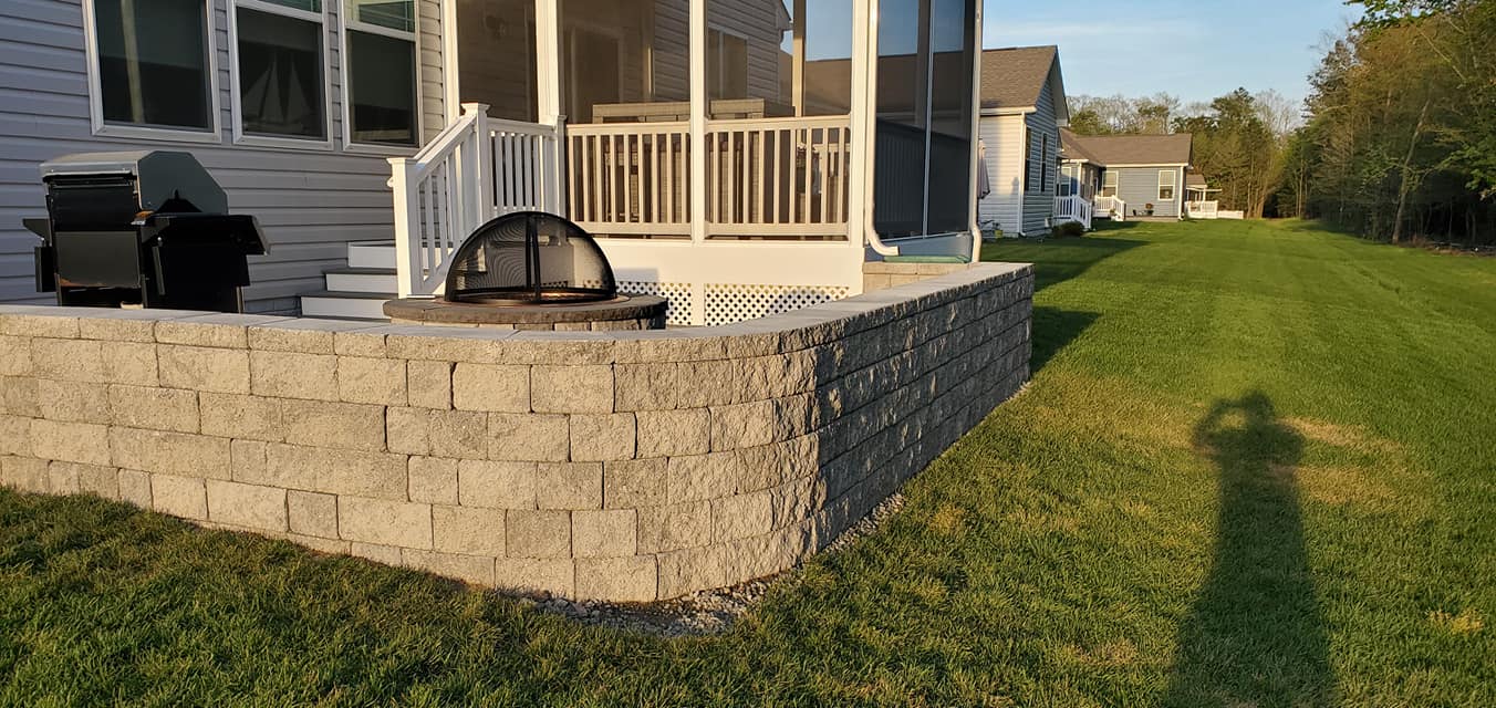 A house with a screened in porch and a brick wall in front of it.