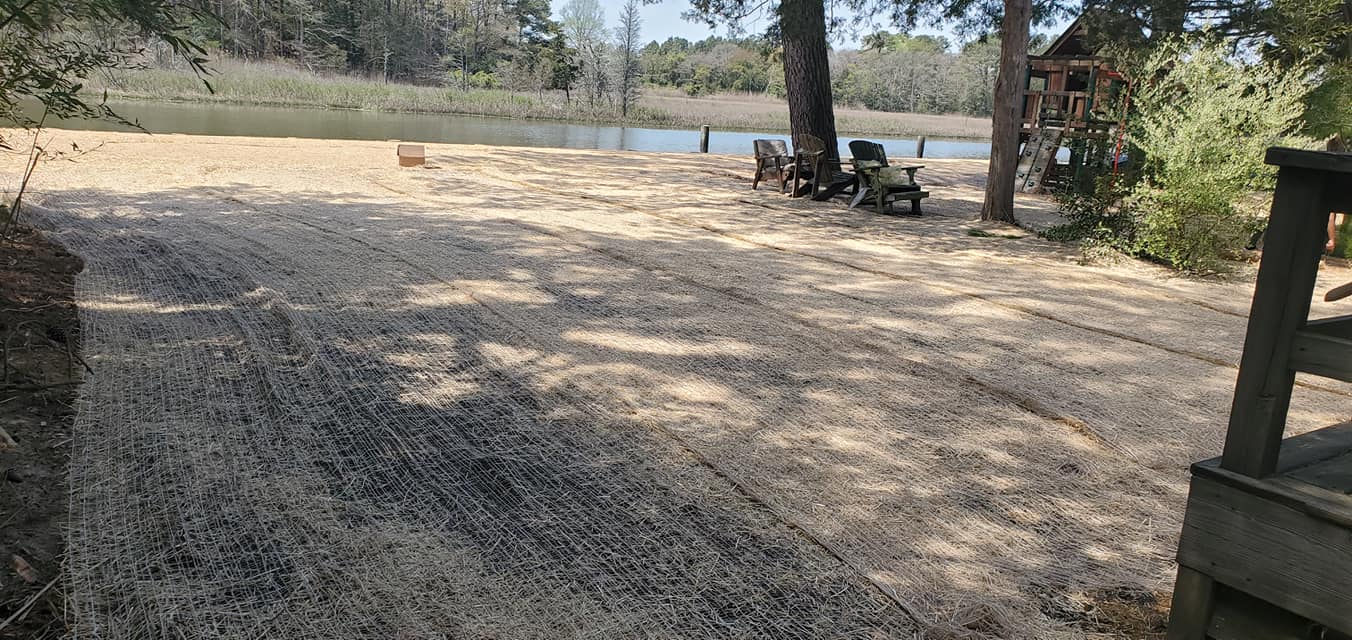 A dirt road leading to a lake with trees in the background.