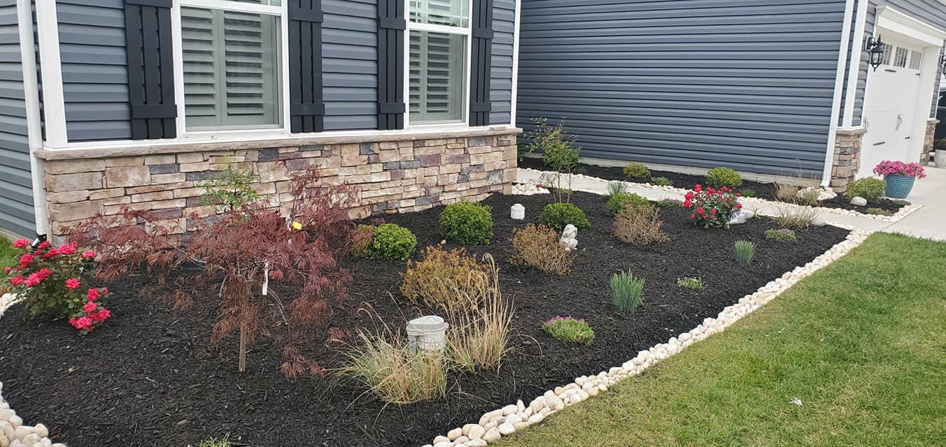 A house with a lush green lawn and a garden in front of it.