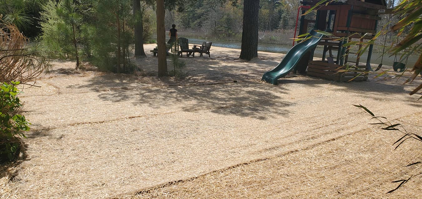 A playground with a slide and a tree house in the background.