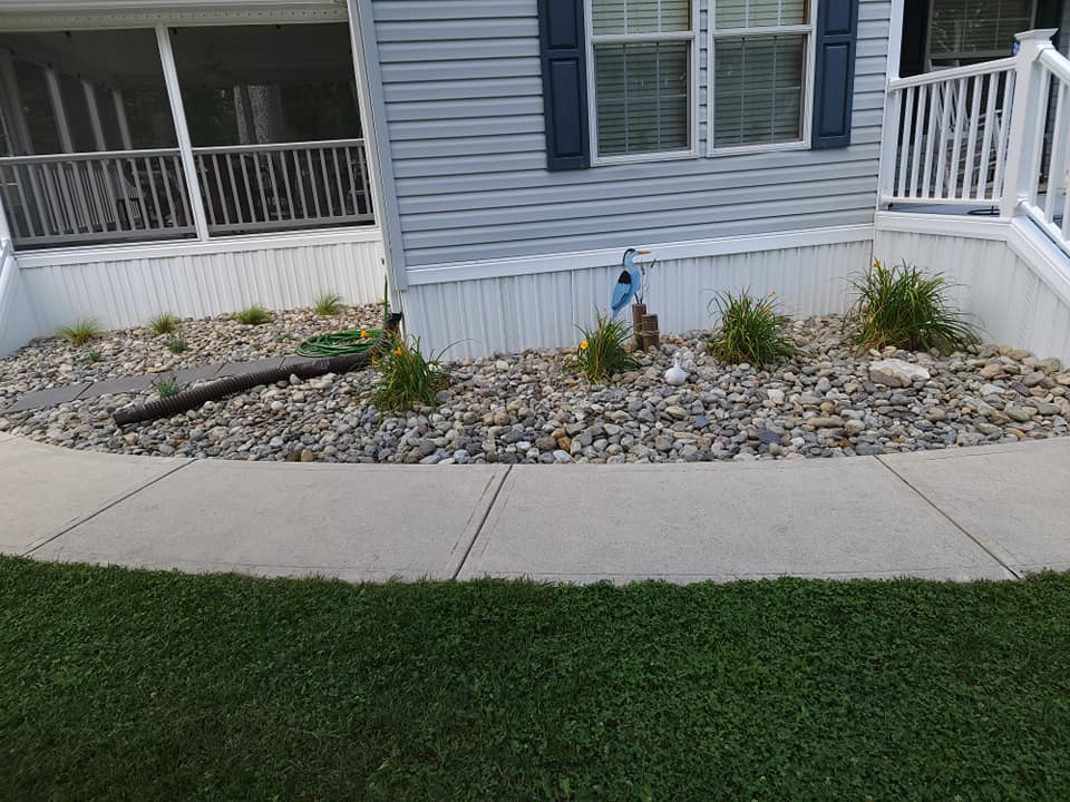 A walkway leading to a mobile home with a garden in front of it.