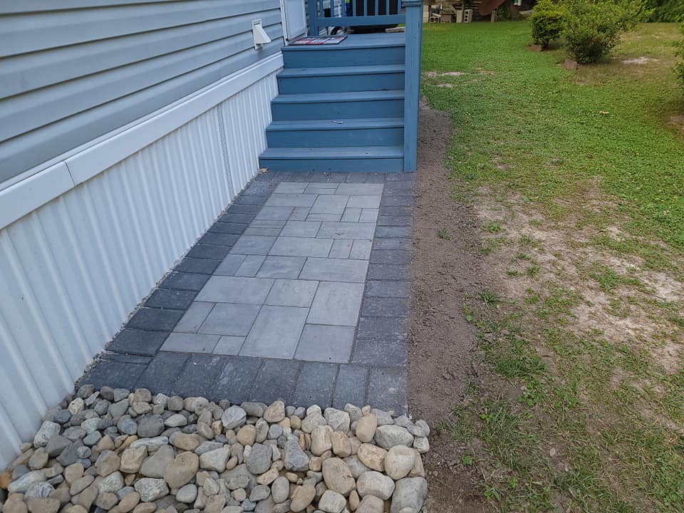 A stone walkway leading to a porch of a mobile home