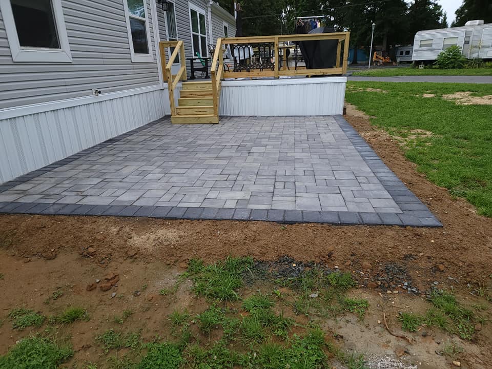 A patio with a wooden deck next to a mobile home.