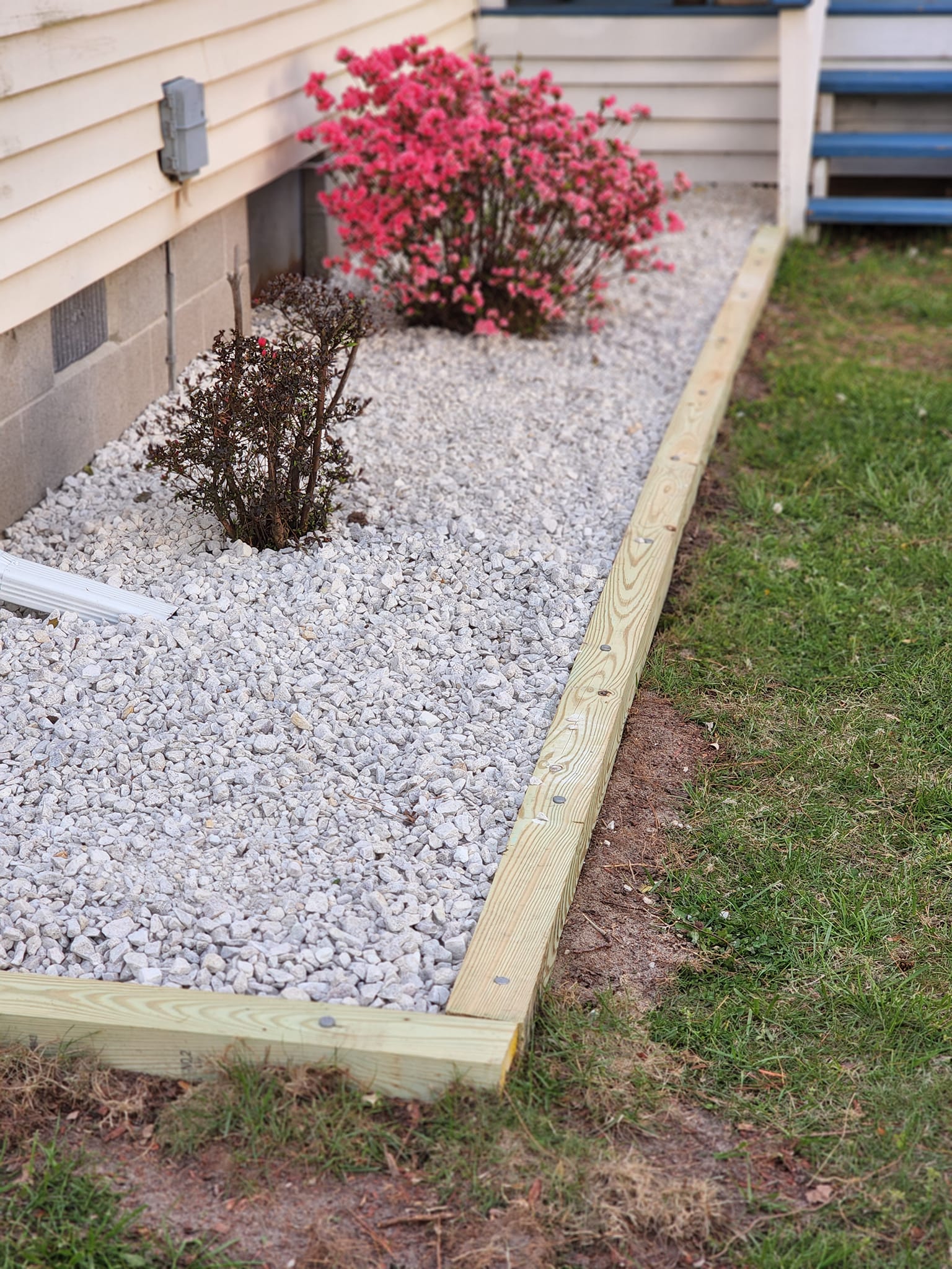 A garden with gravel and flowers in front of a house.