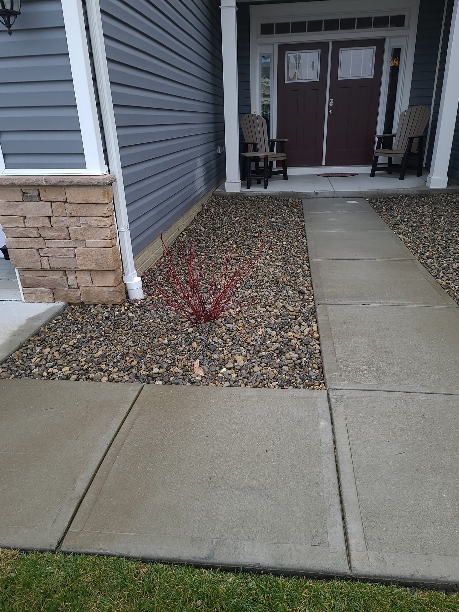 A concrete walkway leading to the front door of a house.