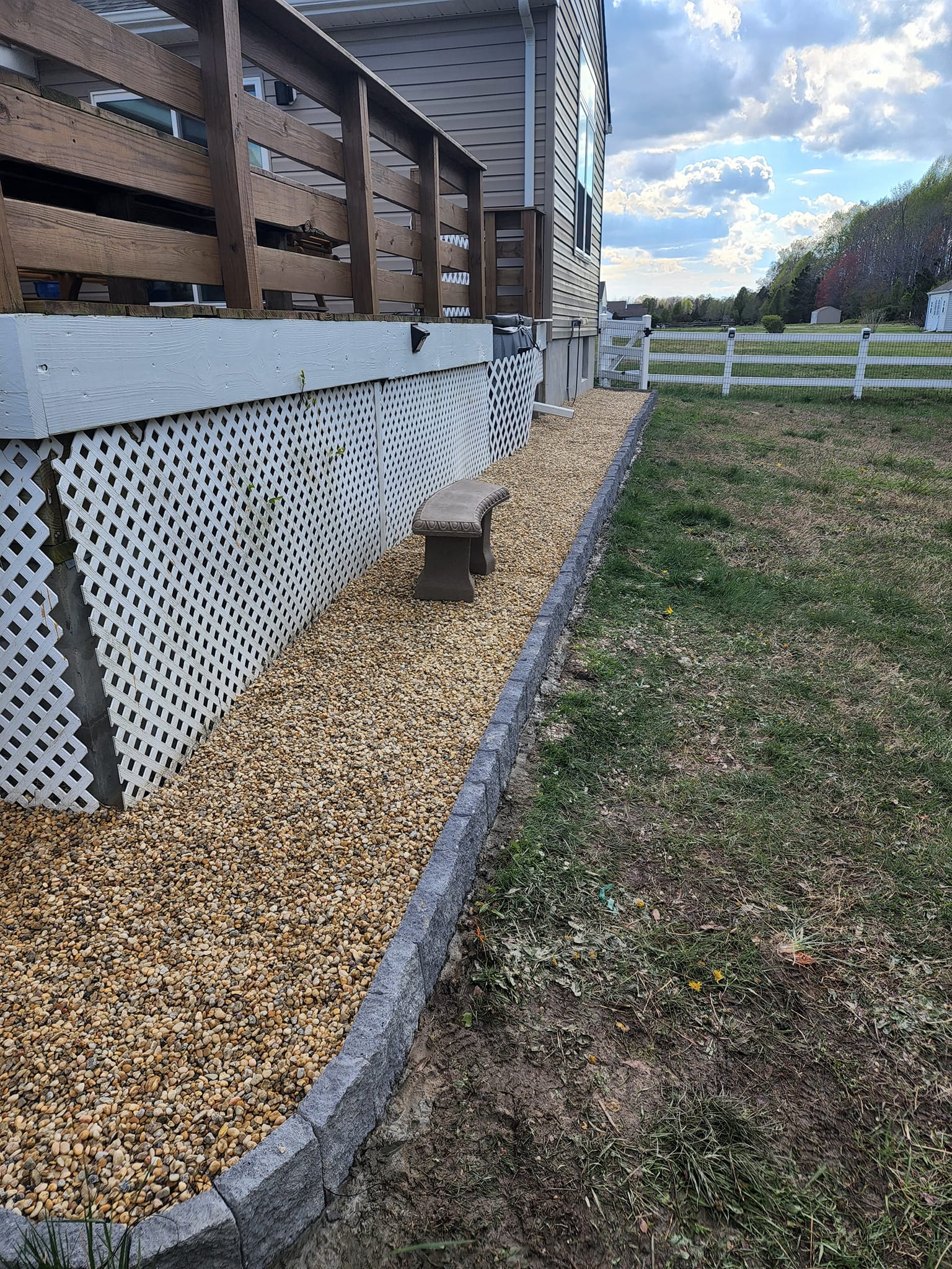 A sidewalk leading to a house with a bench and a fence.