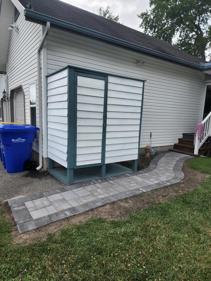 A white house with a blue trash can in front of it.