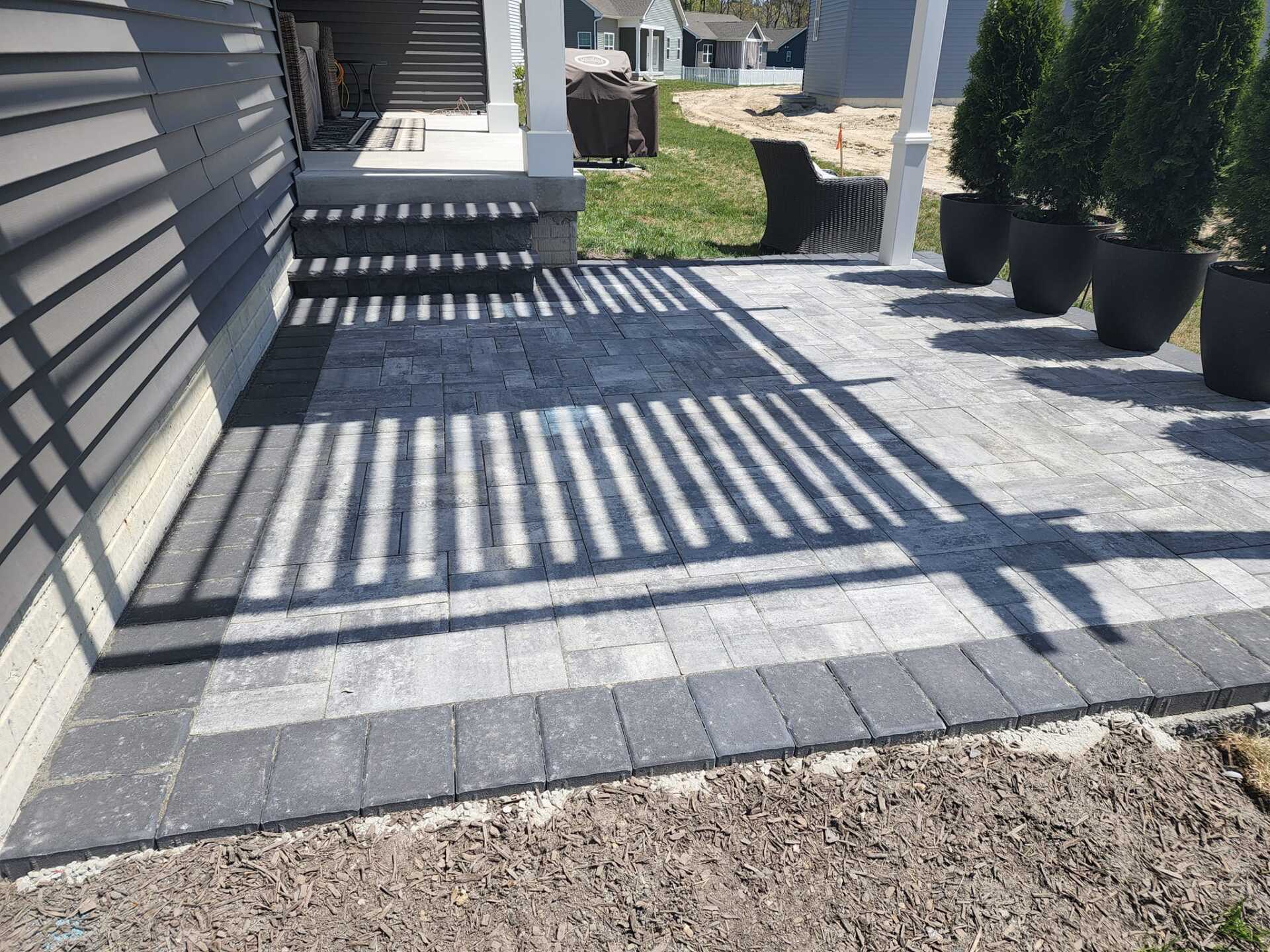 A shadow of a person is cast on a brick walkway in front of a house.