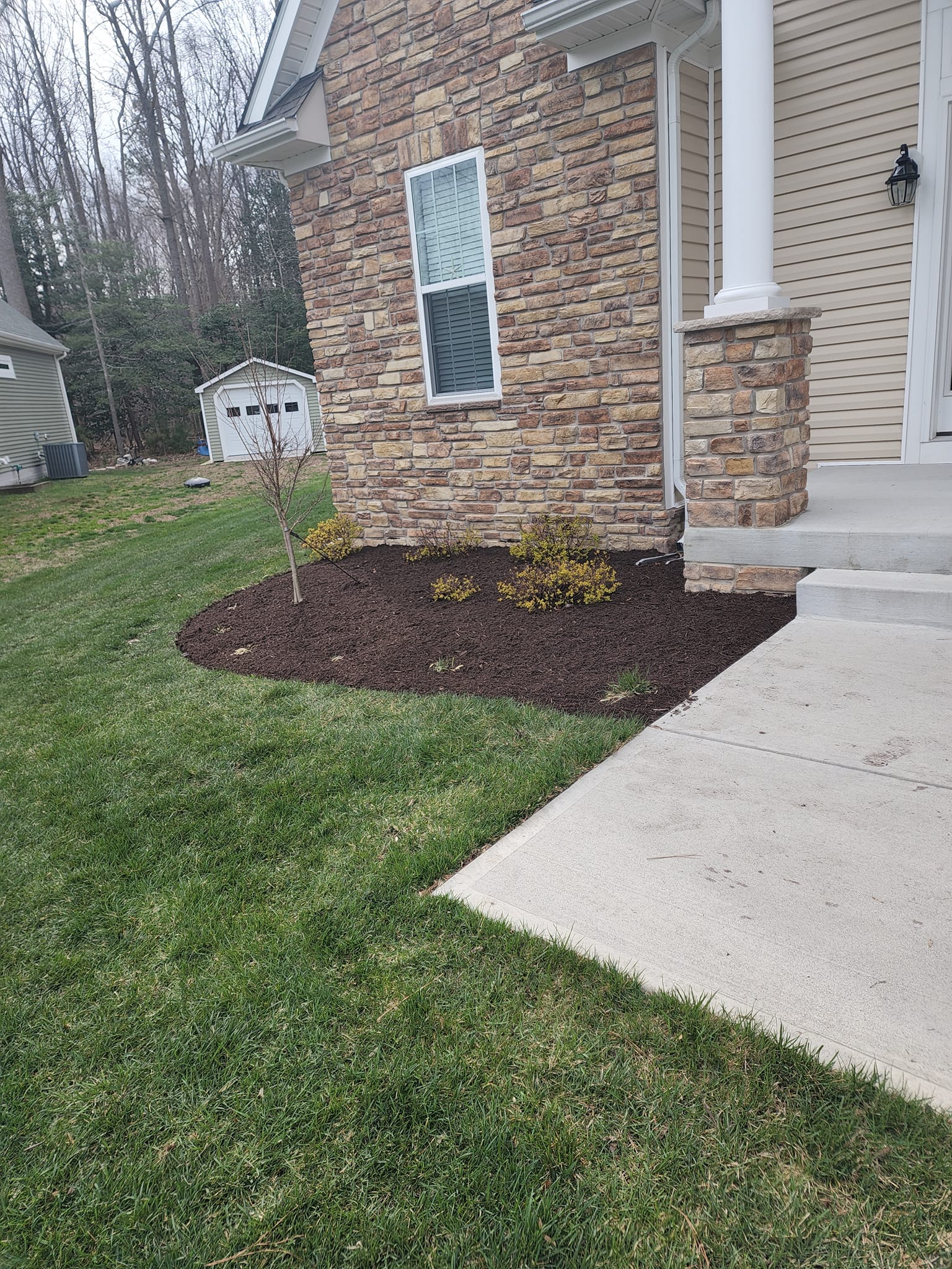 A house with a brick wall and a lush green lawn in front of it.