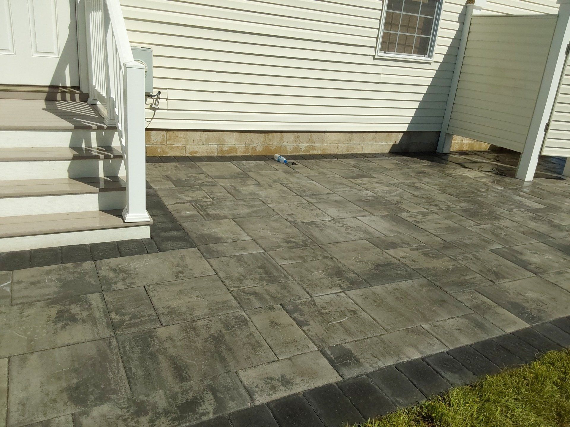 A patio with stairs and a white house in the background