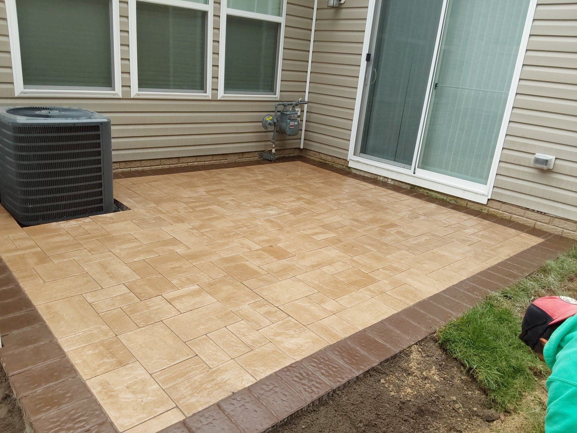 A patio is being built in front of a house with a sliding glass door.