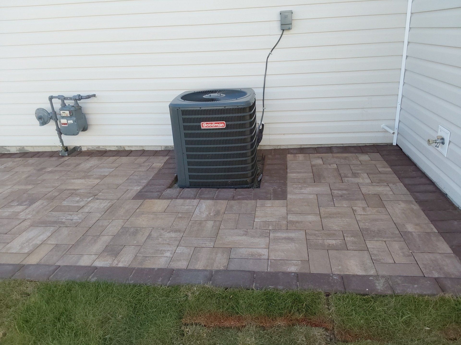 An air conditioner is sitting on a patio next to a house.