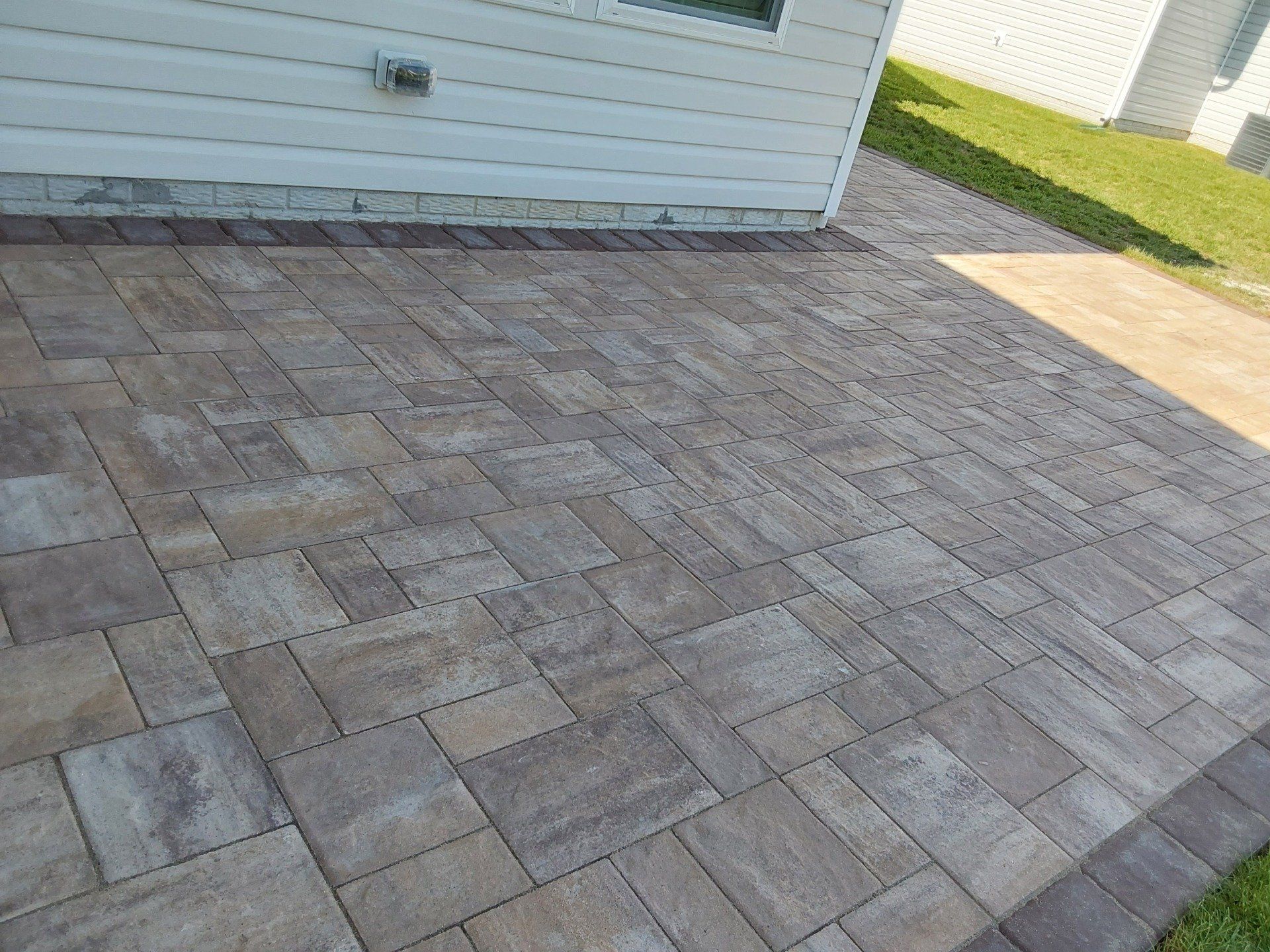 A brick walkway leading to a house with a white house in the background.