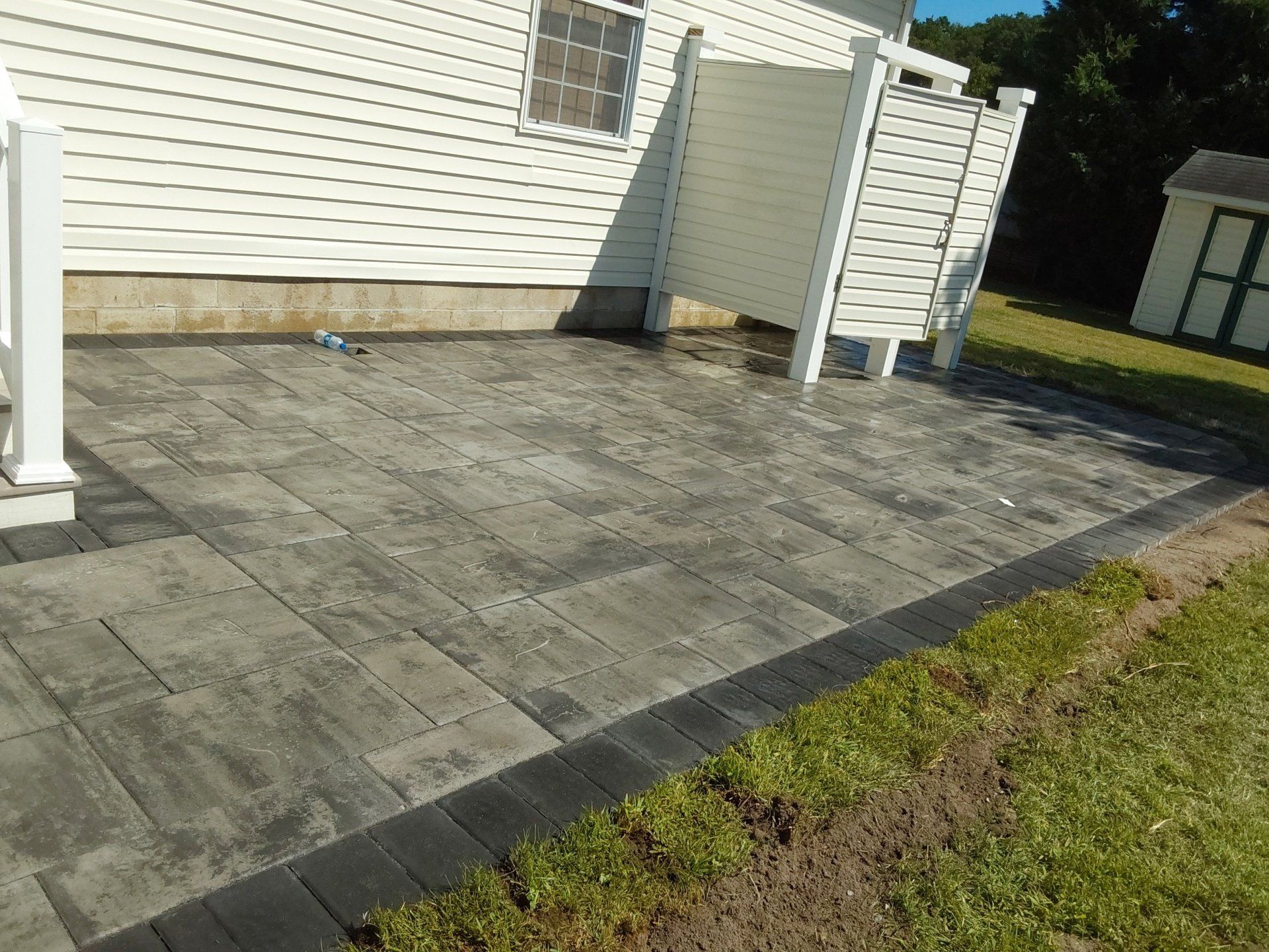 A patio with a white fence and a white house in the background