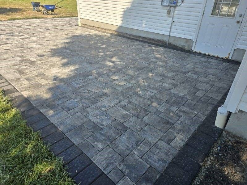 A brick patio is being built in front of a house.