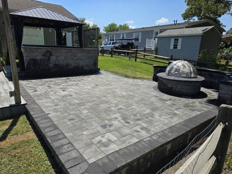 A patio with a gazebo and a fire pit in front of a mobile home.