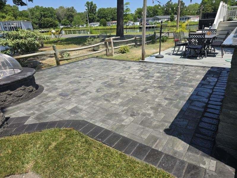 A patio with a fire pit , tables and chairs and a fountain.